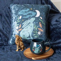 Midnight Hare Cushion in steel blue velvet featuring an elegant moon gazing hare illustration, perfect for adding a magical touch to home decor.